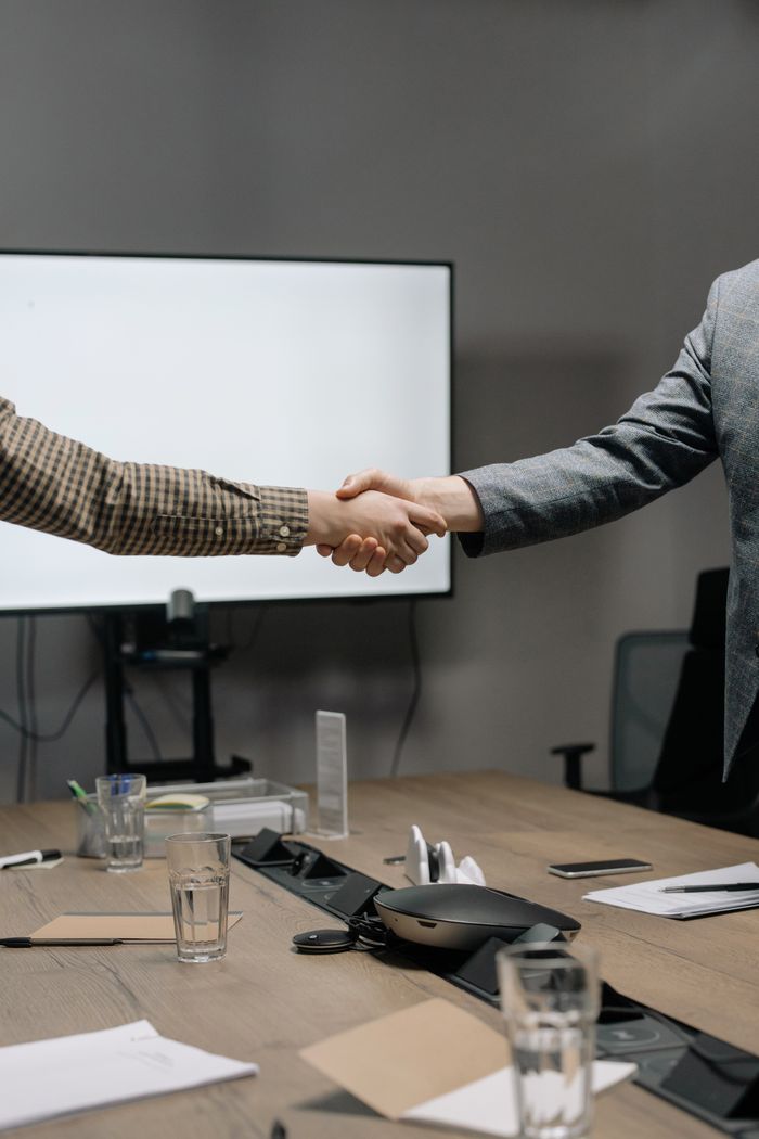 Mastering the First Impression: Your intriguing post title goes here Two business professionals shaking hands in a modern meeting room, symbolizing successful collaboration.
