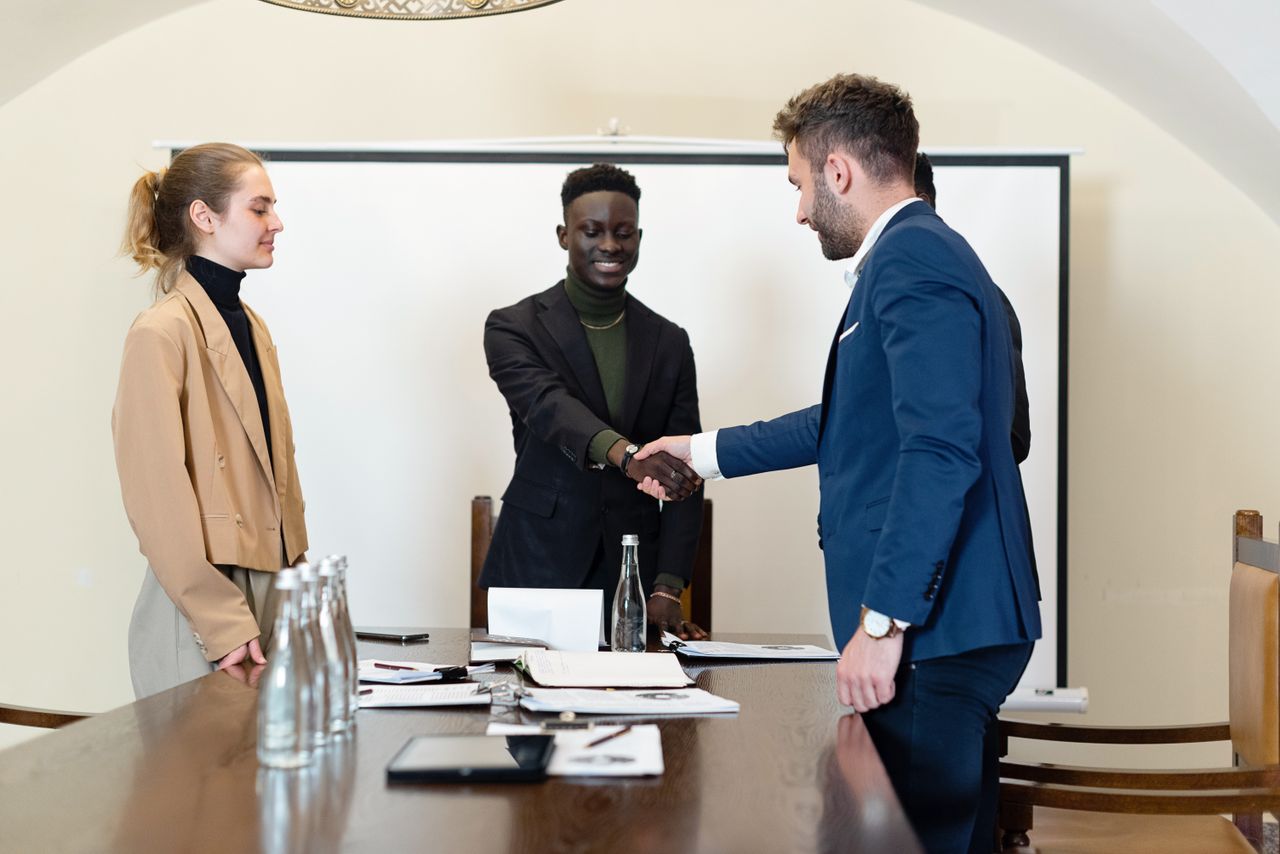 Crafting Captivating Headlines: Your awesome post title goes here A diverse group of business professionals in a meeting room, shaking hands as a sign of agreement.